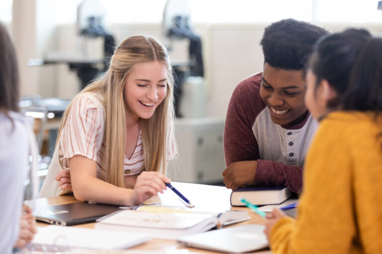 Diverse group of young adults collaborating and laughing together during a study session
