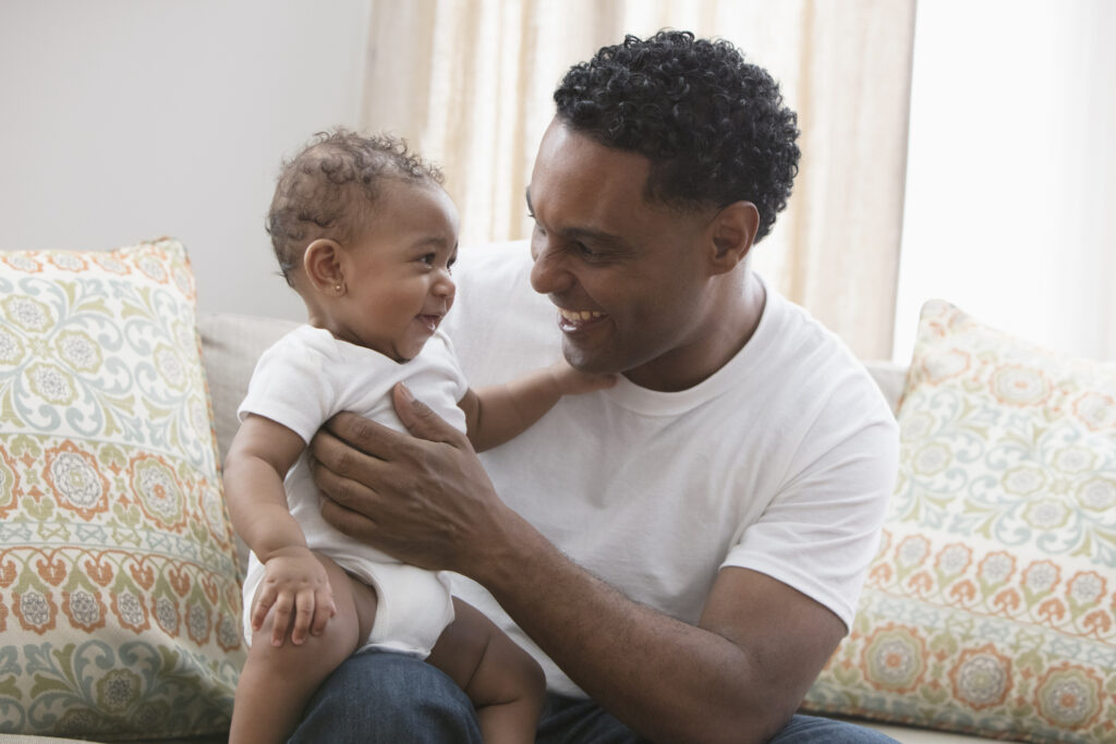 Father playing with his daughter sitting at the sofa