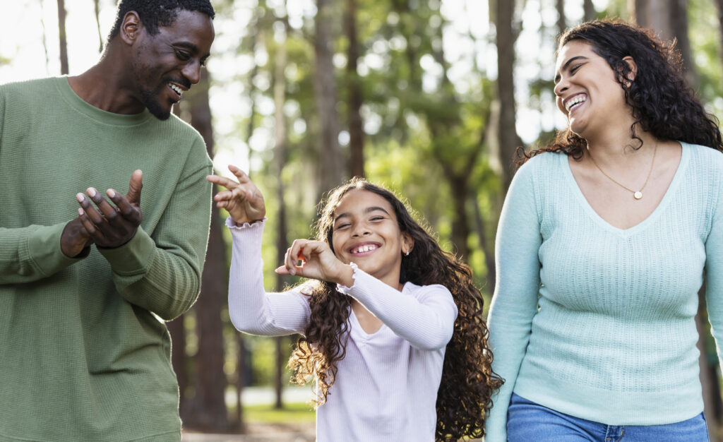 Multiracial girl with mother and friend, dancing in park